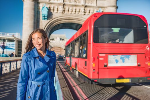 London woman walking commute on Tower Bridge city street using public transport bus commuting in the morning. Happy young Asian british business worker going to work or tourist city travel.