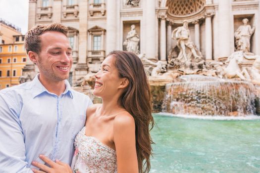Rome couple on romantic date by Trevi Fountain in Roma, Italy. Romantic luxury honeymoon Europe cruise travel tourists lovers traveling in european city. Asian woman falling in love with Italian man.