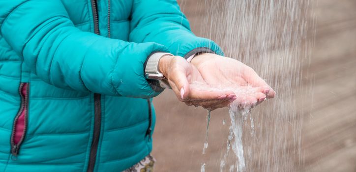 Thirsty woman capturing water from the shower with her hands outdoor in the countryside.