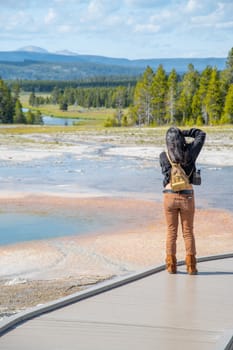 Back view of female tourist taking images of Yellowstone National Park.