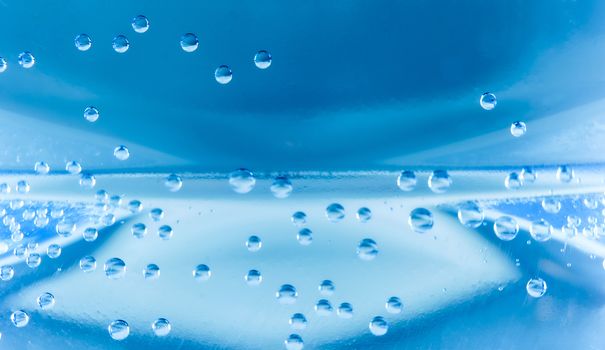 Macro shot of water with bubbles inside a plastic bottle with light and colors effects