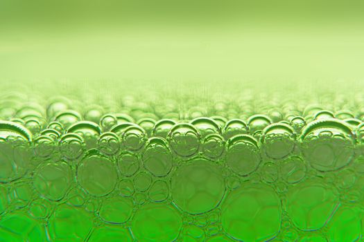 Abstract macro clean green foam shot background of soap bubbles with light and color reflections effects