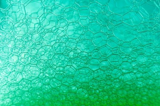 Abstract macro clean green foam shot background of soap bubbles with light and color reflections effects