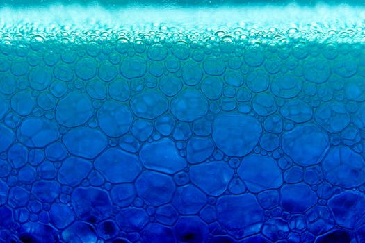 Abstract macro clean blue foam shot background of soap bubbles with light and color reflections effects