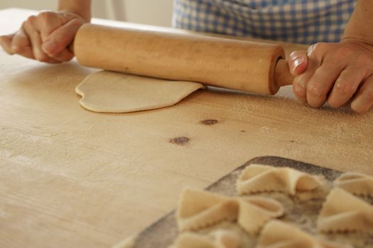 Close up process of homemade vegan farfalle pasta with durum wheat flour. The cook uses a rolling pin to stretch the dough, traditional Italian pasta, the woman cooks the food in the kitchen