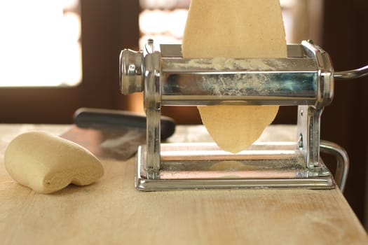 Making homemade fresh pasta: backlit close up of the details of the pasta rolled out by the metal manual pasta machine