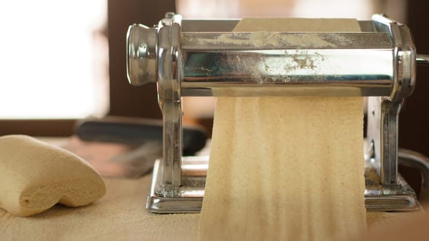 Making homemade fresh pasta: backlit close up of the details of the pasta rolled out by the metal manual pasta machine