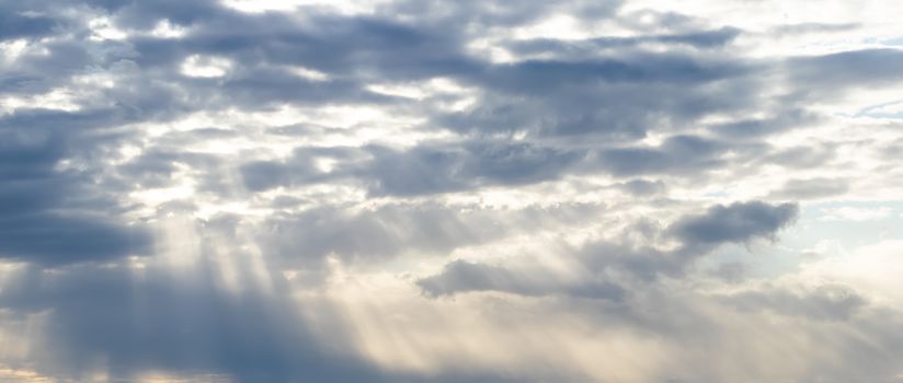 Sun rays breaking through cumulus clouds. The concept of divine light, a glimmer of hope or overcoming difficulties. Spiritual religious abstract background.