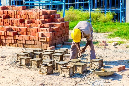 Karnal, Haryana, India - march 2018 : man making up of bricks near the big buildings in karnal