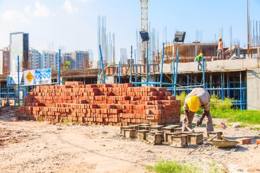 Karnal, Haryana, India - march 2018 : man making up of bricks near the big buildings in karnal