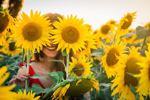 Happy woman with sunflower enjoying nature and laughing on summer sunflower field.