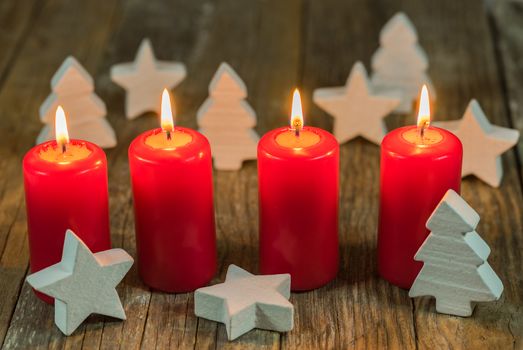 Christmas or advent four red burning candles with stars and trees decoration