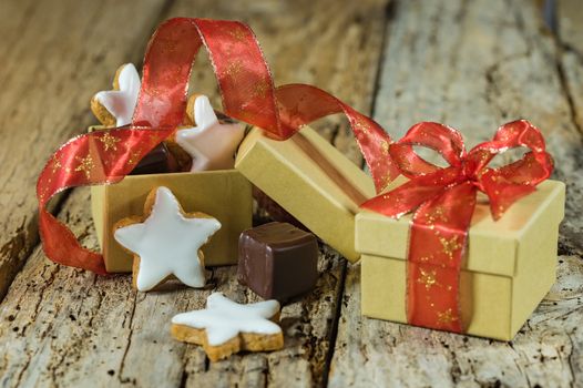 Christmas star biscuits and chocolate gift with red ribbon on wooden table
