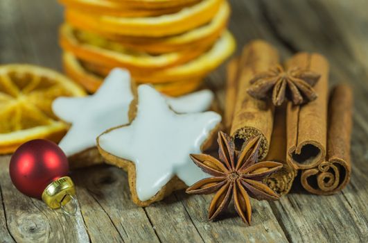 Christmas still life with star biscuites, cinnamon, anise and orange slices on wooden table