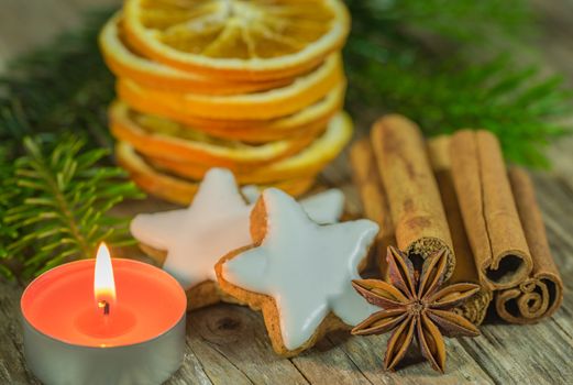 Christmas composition of star cookies, spices, orange slices and candlelight