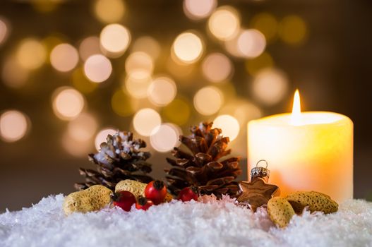 Advent or Christmas candle with ornaments decoration on snow and blurred lights background