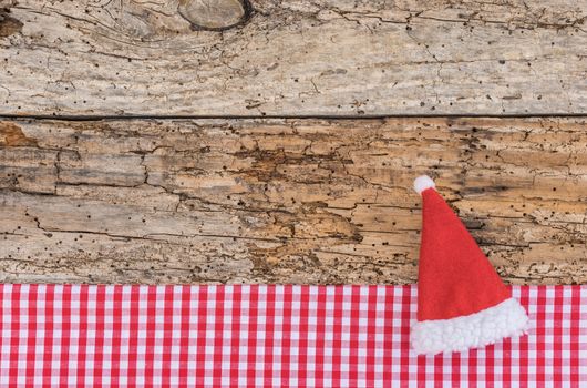 Christmas background with Santa Claus cap on rustic wood, copy space