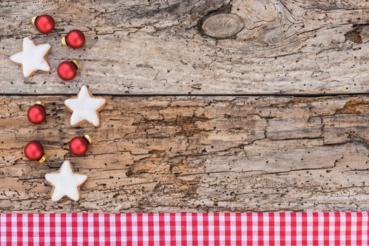 Christmas star shape cookies, balls and red checkered fabric border on old wooden table, copy space