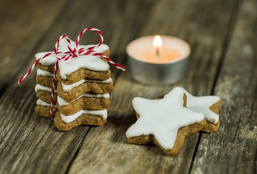 Advent and Christmas still life with stack of star cookies and candlelight on wood