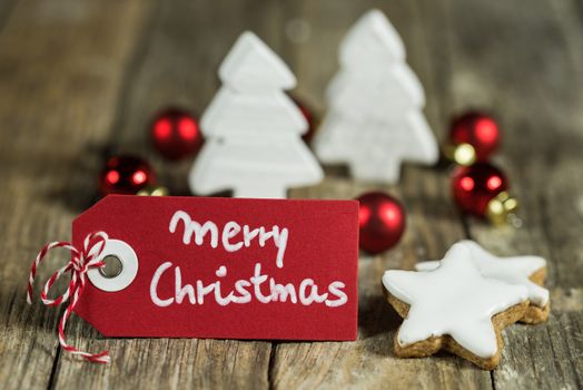 Merry Christmas greeting with star shape cookies, red balls and white wooden christmas trees