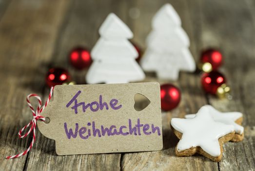 Label with handwritten greeting in german, Frohe Weihnachten, means Merry Christmas, with xmas ornaments