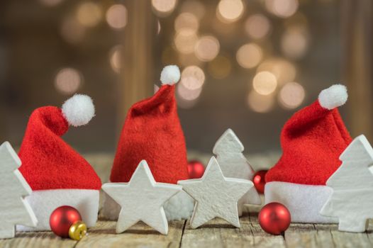 Santa caps with christmas decoration on wooden table with sparkling lights bokeh