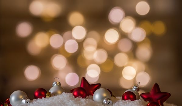 Red and white christmas decorations on snow with sparkling lights background