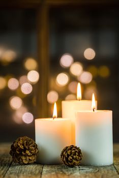 Three Advent and Christmas candle flames decoration with blurred lights background