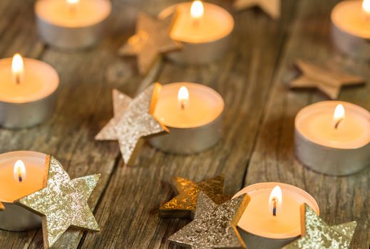 Christmas and Advent candlelights and golden star shape decoration on wood