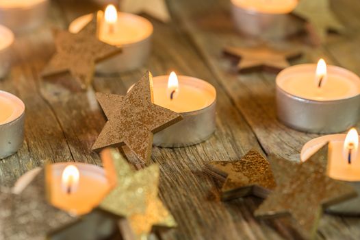 Festive advent night with candle flames and star ornaments on wood