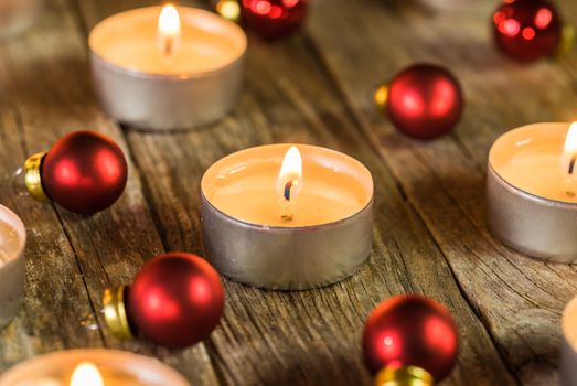 Burning Advent candle flames with red christmas balls ornaments