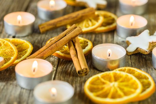 Advent candlelights, star shape biscuits, cinnamon and orange slices on wooden table