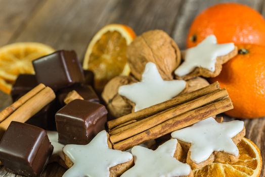 Christmas star cookies, chocolate, cinnamon and oranges on wooden table