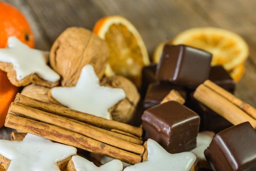 Christmas food, sweet star shape biscuits, chocolates, nuts, oranges and cinnamon