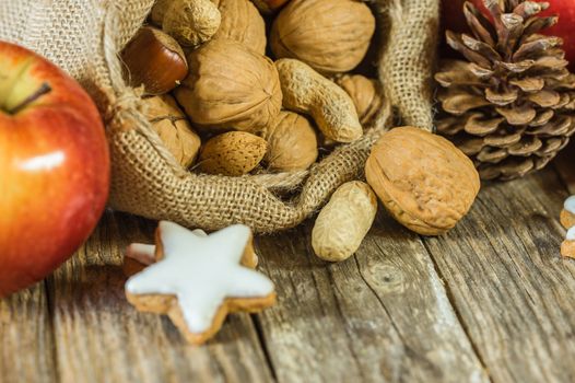 Christmas food composition with nuts in santa claus bag, red apple, and star shape cookie