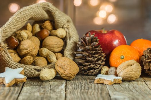 Christmas food with nuts in santa claus bag, red apple, orange fruit and star shape cookie