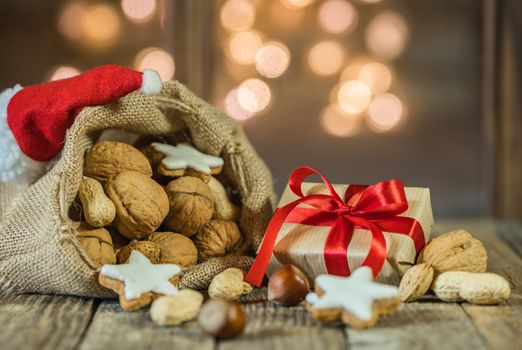 Santa Claus bag with nuts, cookies, christmas gift and sparkling lights window background