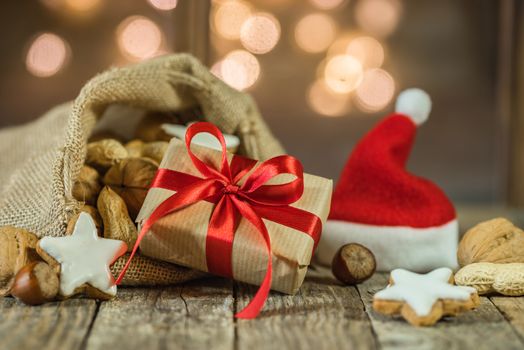 Advent and Christmas gift and santa claus bag and cap with nuts and cookies with sparkling lights background