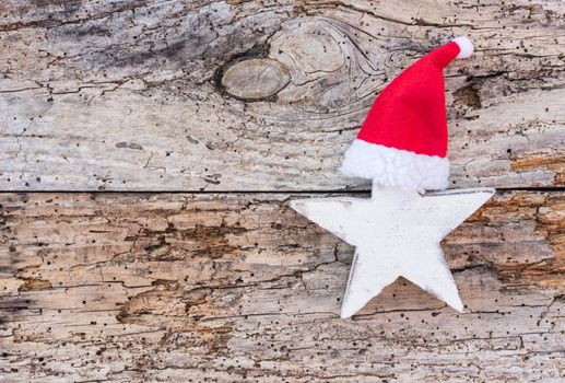 White Christmas star with red Santa hat on old wooden background with copy space