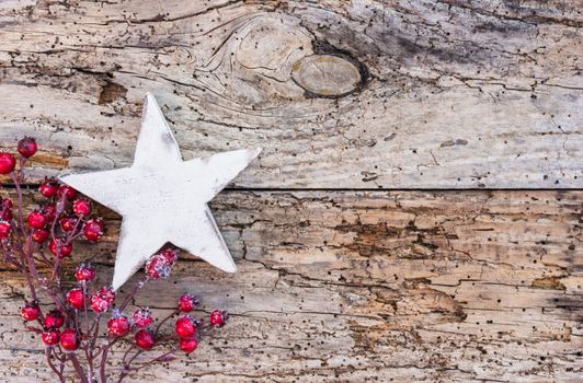 Christmas decoration with white star shape and red berries on old wood background with copy space