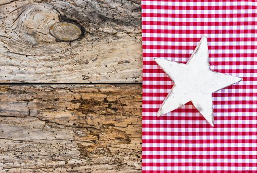 Wooden Christmas star on red checkered fabric and old wood, copy space