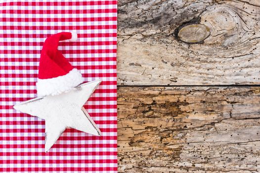 Christmas and Advent background, white star shape with red santa hat on rustic wood, copy space