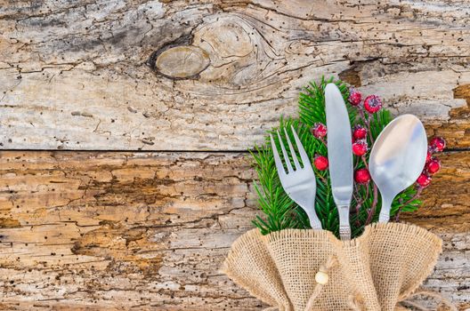 Christmas holiday dinner celebration, table place setting with cutlery on rustic wooden background