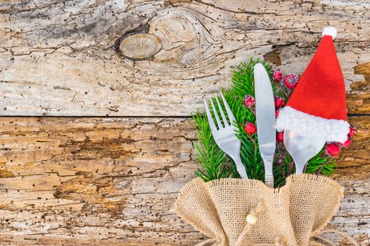 Christmas table place setting with santa hat, holidays celebration copy space on rustic wood background