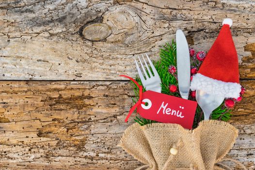 Christmas or Advent dinner table place setting with cutlery and red santa hat decoration