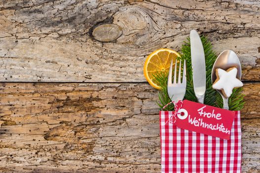 Christmas cutlery on wooden table background with german label text, Frohe Weihnachten, means Merry Christmas 