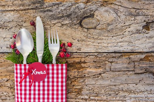 Christmas dinner table place setting with tag Xmas on rustic wood background