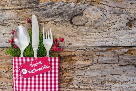 Christmas cutlery on wooden table background with german label text, Frohe Weihnachten, means Merry Christmas 