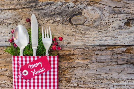 Christmas table place setting with tag Merry Xmas, rustic wood background, copy space