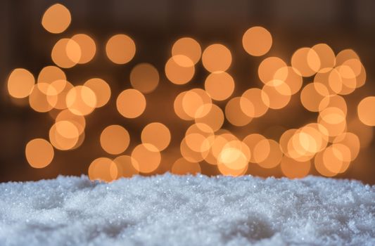 Sparkling white snow with golden warm blurred lights background with copy space